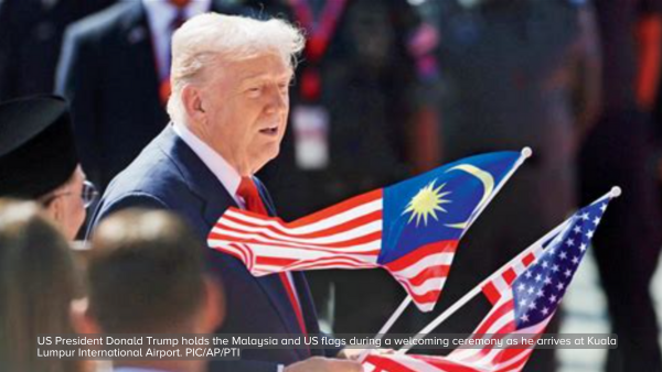US President Donald Trump holds the Malaysia and US flags during a welcoming ceremony as he arrives at Kuala Lumpur International Airport. PIC/AP/PTI